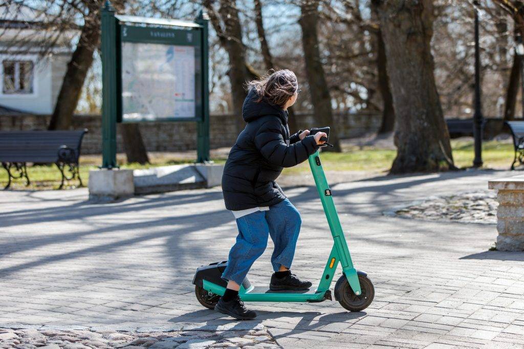 Teenage girl riding scooter on pavement